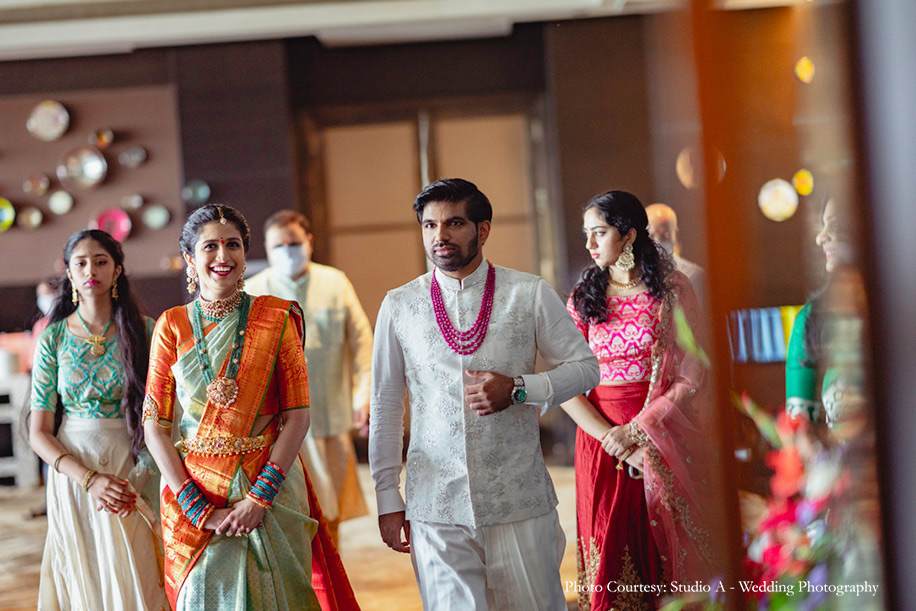 Bride wearing green and orange kanjeewaram and groom wearing white nehru jacket for engagement