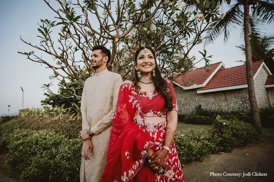 Bride wearing red embroidery lehenga and groom wearing beige kurta for the Welcome Party.