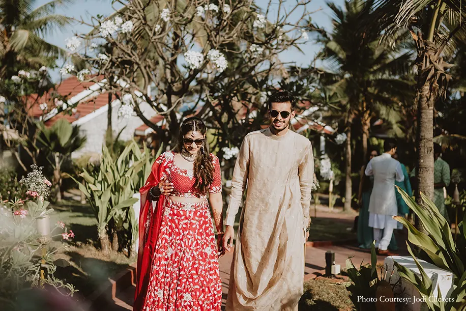 Bride wearing red embroidery lehenga and groom wearing beige kurta for the Welcome Party.