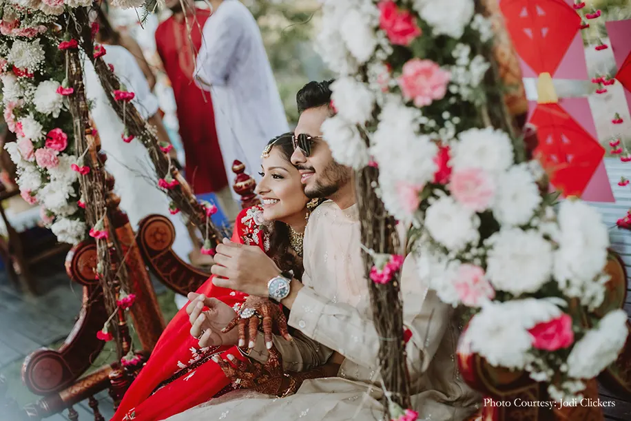 Bride wearing red embroidery lehenga and groom wearing beige kurta for the Welcome Party.