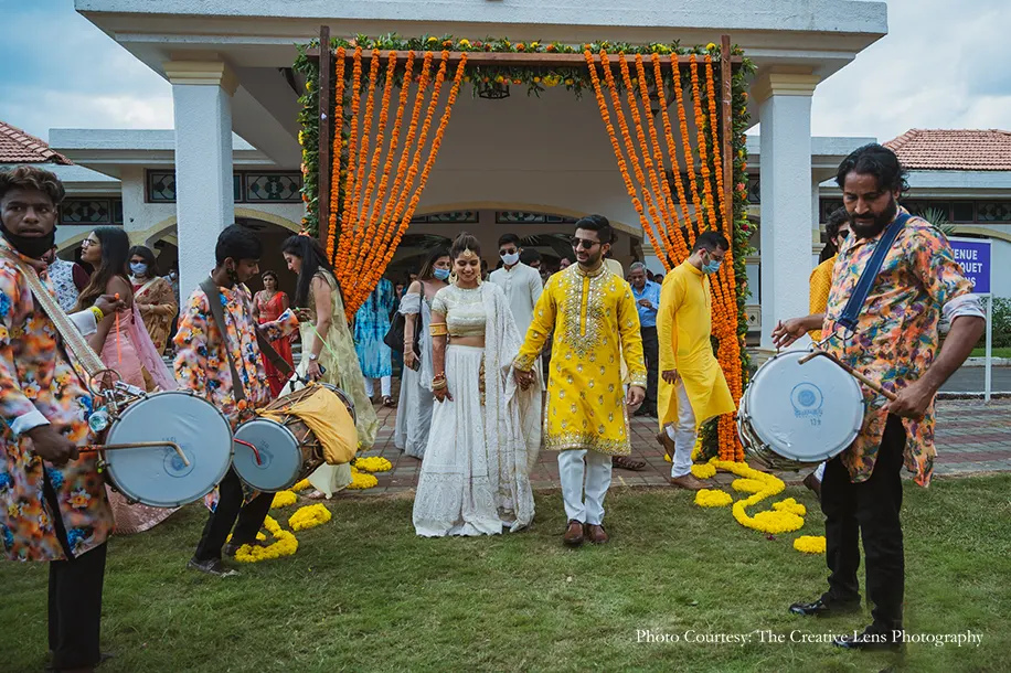 Bride wearing white chikankari lehenga and groom wearing yellow mirror work lehenga for the welcome dinner